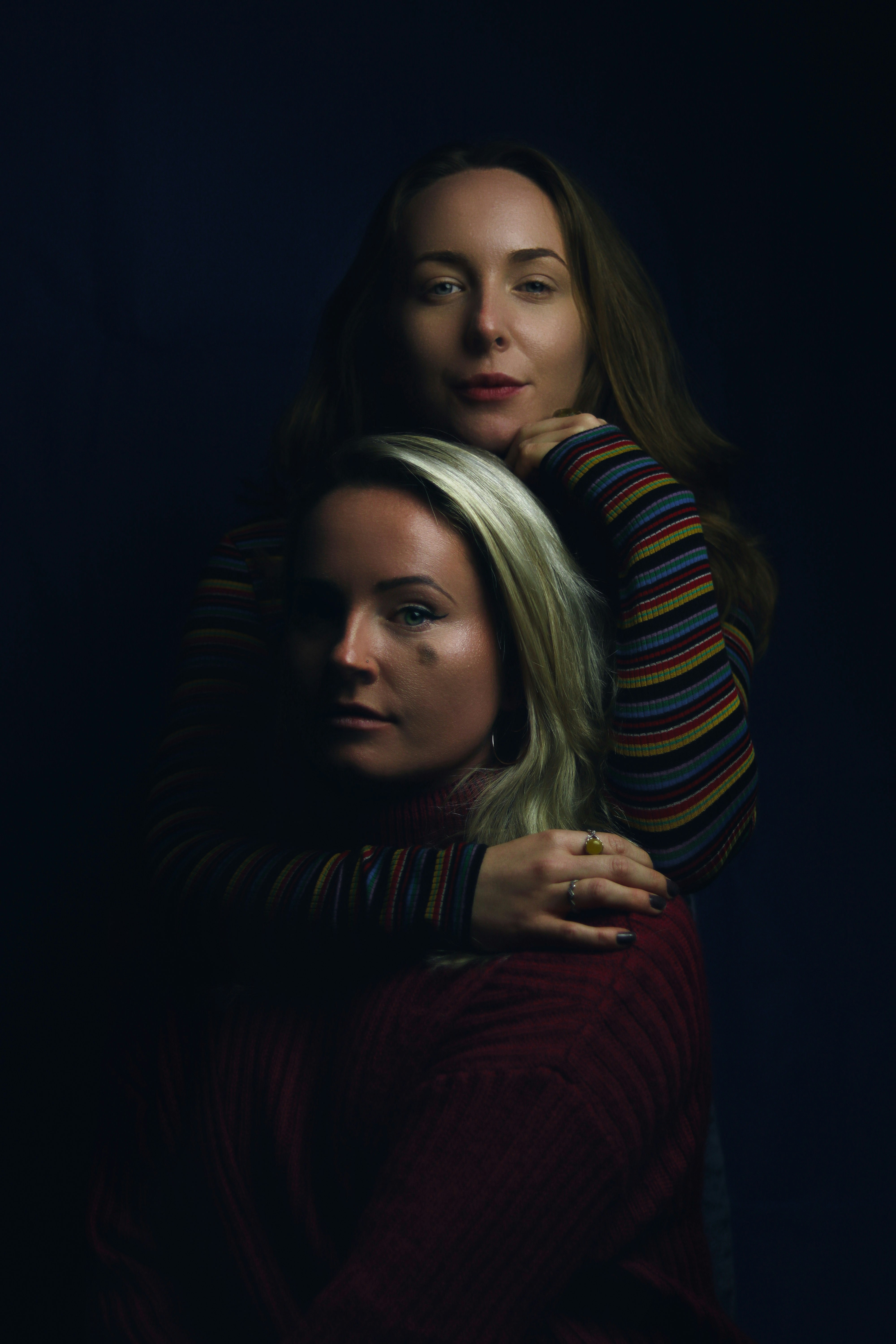 woman in striped shirt back hugging woman